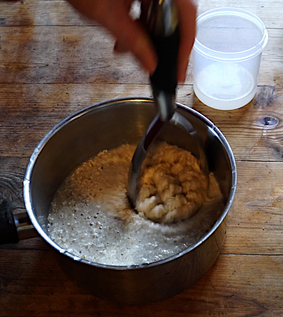 Mashing the oats with a hand masher in a saucepan